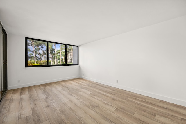 unfurnished room with light wood-type flooring and baseboards