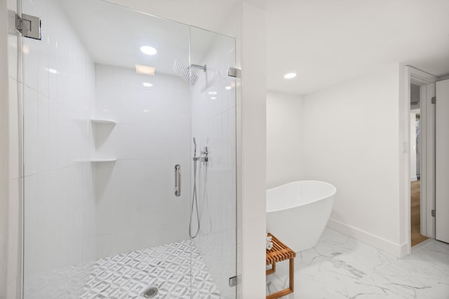 bathroom featuring marble finish floor, a freestanding tub, a shower stall, and baseboards