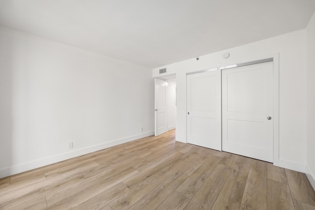 unfurnished bedroom with light wood-style floors, a closet, visible vents, and baseboards