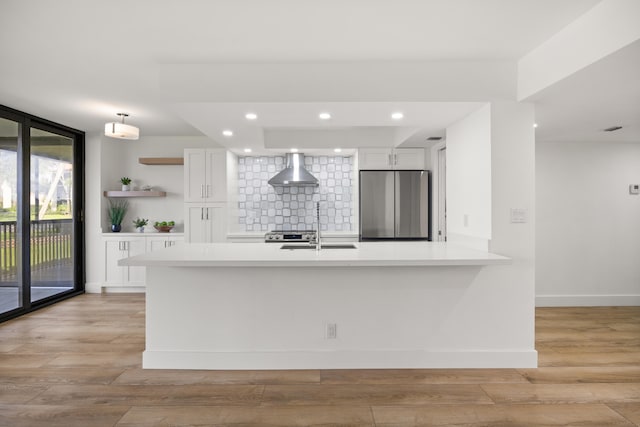 kitchen with tasteful backsplash, wall chimney exhaust hood, freestanding refrigerator, light countertops, and floor to ceiling windows