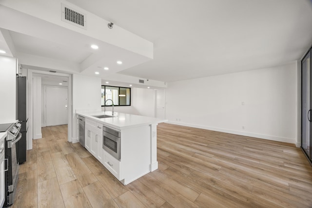 kitchen featuring light wood finished floors, visible vents, white cabinets, stainless steel appliances, and a sink