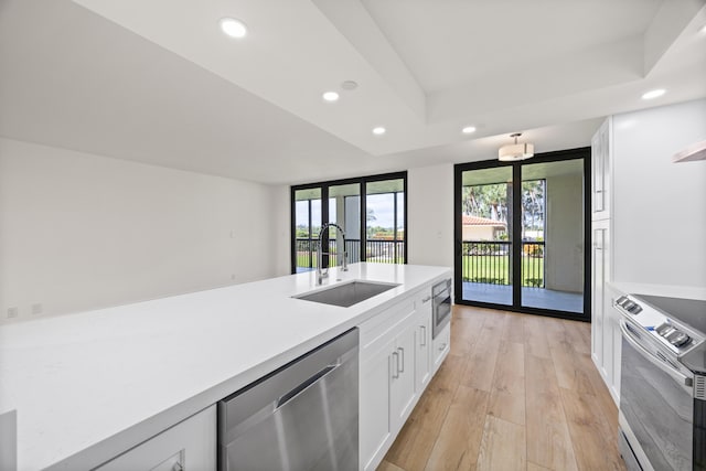 kitchen featuring recessed lighting, a sink, white cabinets, light wood-style floors, and appliances with stainless steel finishes