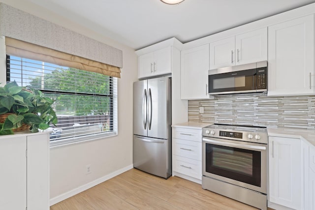 kitchen featuring appliances with stainless steel finishes, light wood-type flooring, white cabinets, and tasteful backsplash