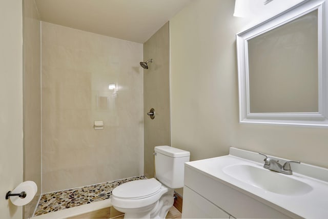 bathroom with vanity, toilet, and a tile shower