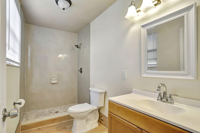 bathroom featuring hardwood / wood-style flooring, vanity, toilet, and tiled shower