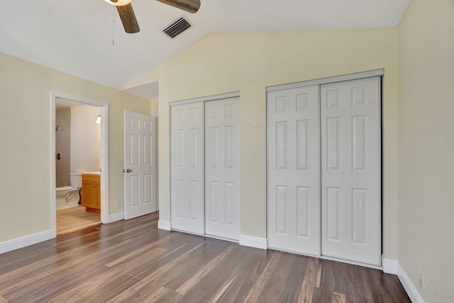 unfurnished bedroom with ceiling fan, dark hardwood / wood-style flooring, ensuite bathroom, vaulted ceiling, and two closets