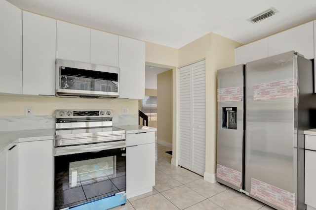 kitchen with light tile patterned floors, stainless steel appliances, white cabinetry, and a wealth of natural light