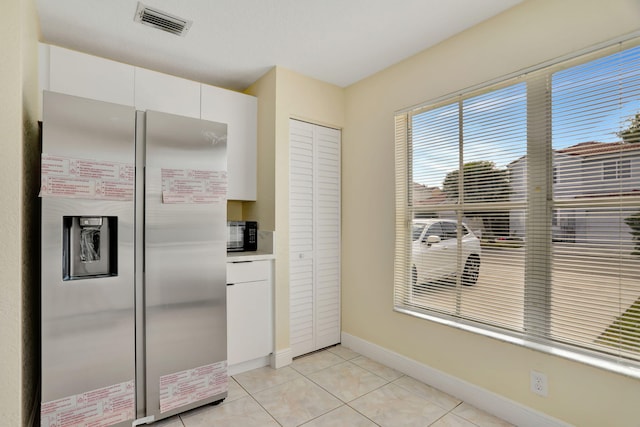 kitchen featuring white cabinets, stainless steel fridge, and light tile patterned flooring