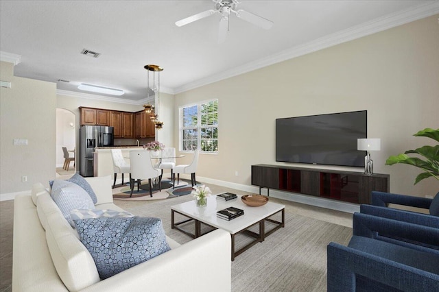 living room with ceiling fan, light colored carpet, and crown molding