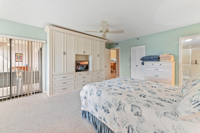 bedroom featuring a textured ceiling, ensuite bath, a closet, carpet flooring, and ceiling fan