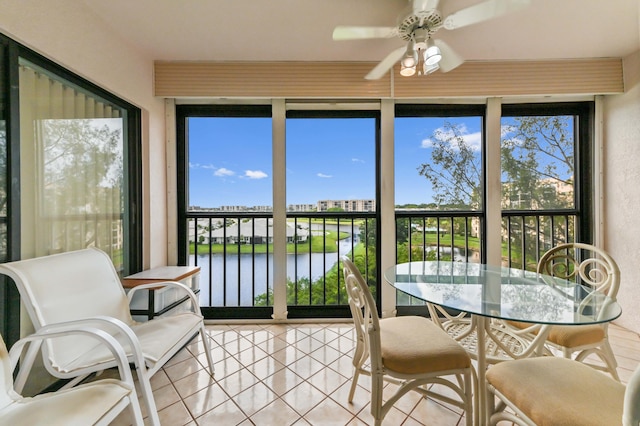 sunroom featuring ceiling fan and a water view