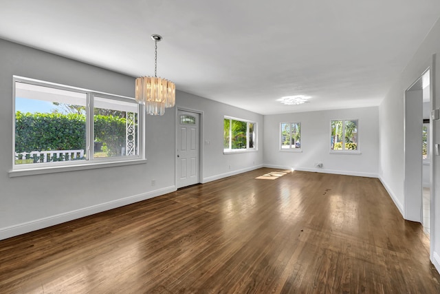 empty room with dark hardwood / wood-style floors and a notable chandelier