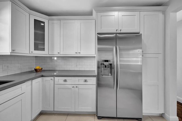 kitchen with decorative backsplash, white cabinetry, and stainless steel refrigerator with ice dispenser