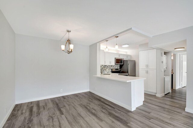 kitchen with decorative backsplash, light hardwood / wood-style flooring, kitchen peninsula, stainless steel appliances, and white cabinets