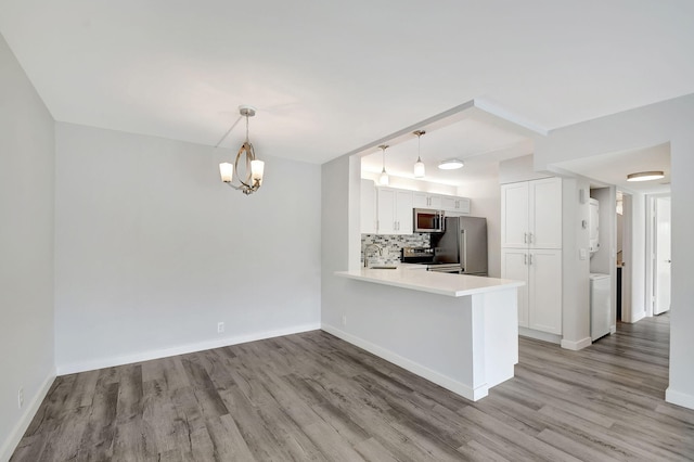 811 Sky Pine Way Unit D2, Greenacres, FL 33415 - kitchen featuring appliances with stainless steel finishes, wood finished floors, decorative backsplash, and a peninsula