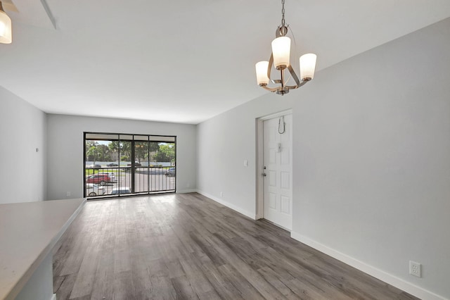 unfurnished living room featuring an inviting chandelier and dark wood-type flooring