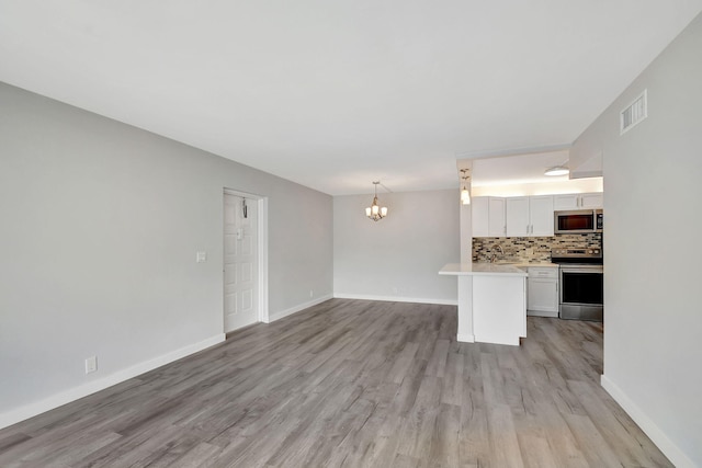 unfurnished living room featuring a chandelier, sink, and light wood-type flooring