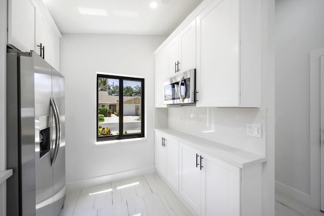 kitchen with tasteful backsplash, appliances with stainless steel finishes, vaulted ceiling, and white cabinets