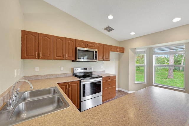 kitchen featuring appliances with stainless steel finishes, sink, and vaulted ceiling