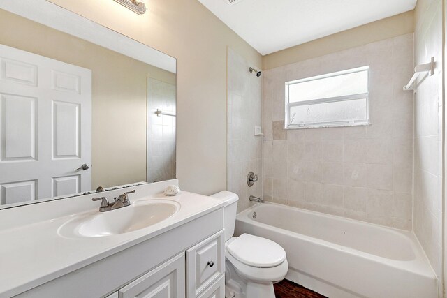 full bathroom featuring hardwood / wood-style floors, vanity, toilet, and tiled shower / bath