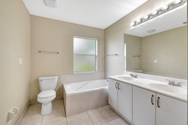 bathroom featuring tile patterned floors, toilet, a textured ceiling, tiled tub, and vanity