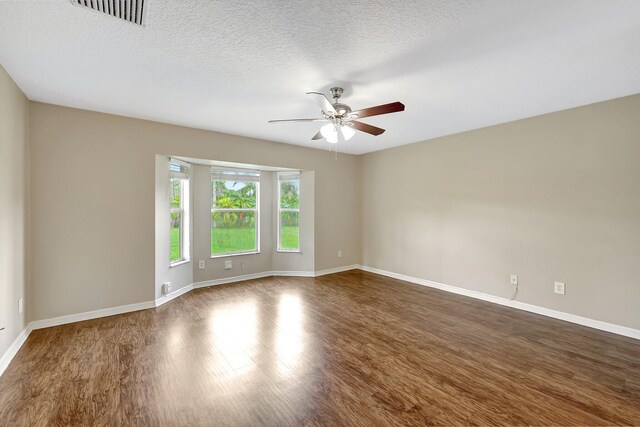 empty room with ceiling fan, a textured ceiling, and dark hardwood / wood-style floors