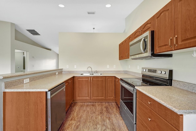 kitchen featuring stainless steel appliances, light wood-type flooring, pendant lighting, sink, and kitchen peninsula