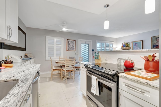 kitchen featuring light tile patterned floors, appliances with stainless steel finishes, white cabinetry, pendant lighting, and light stone counters