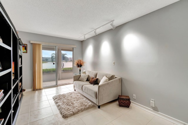 living room featuring a textured ceiling, light tile patterned flooring, and track lighting