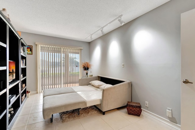 bedroom featuring rail lighting, a textured ceiling, and light tile patterned flooring