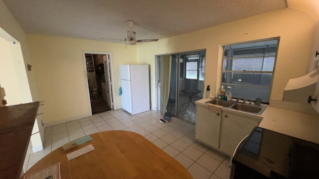 kitchen featuring a textured ceiling, sink, light tile patterned flooring, ceiling fan, and white fridge