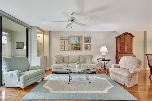 living room featuring ceiling fan, a wall of windows, and light hardwood / wood-style flooring