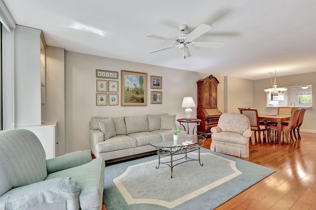 living room featuring light wood-type flooring and ceiling fan with notable chandelier