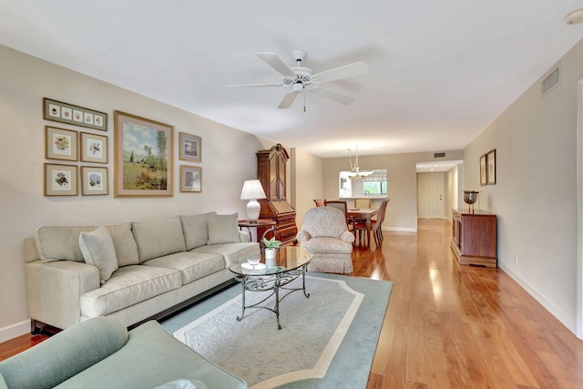 living room with hardwood / wood-style floors and ceiling fan with notable chandelier