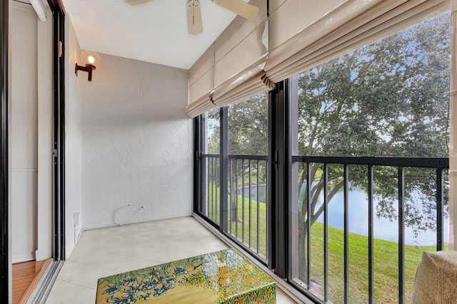 sunroom / solarium with ceiling fan and a water view