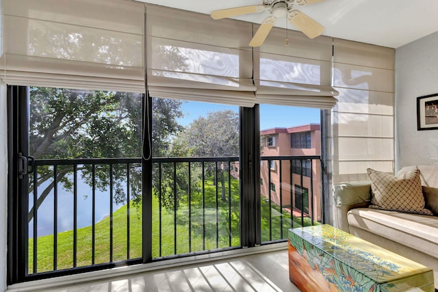 sunroom / solarium featuring ceiling fan and a water view