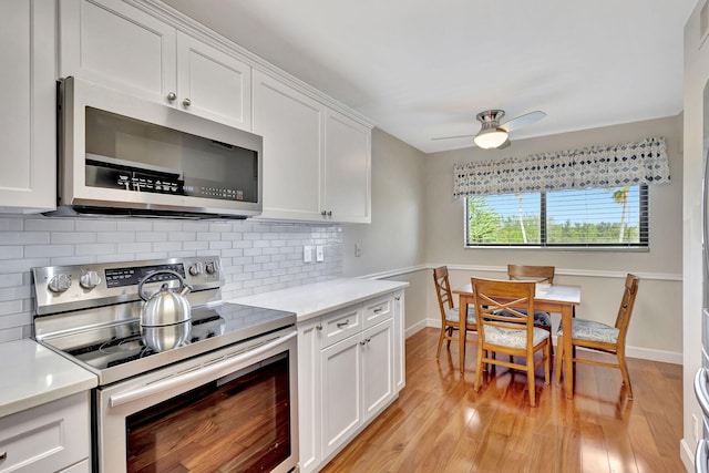 kitchen featuring backsplash, ceiling fan, light hardwood / wood-style floors, white cabinetry, and stainless steel appliances