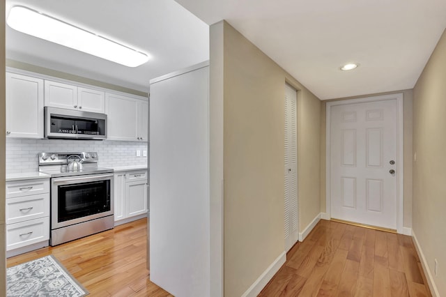 kitchen with appliances with stainless steel finishes, light hardwood / wood-style floors, and white cabinetry