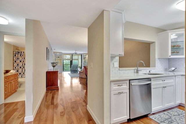 kitchen featuring tasteful backsplash, white cabinetry, dishwasher, and sink