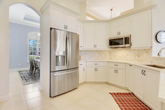 kitchen featuring backsplash, sink, light tile patterned flooring, a raised ceiling, and appliances with stainless steel finishes