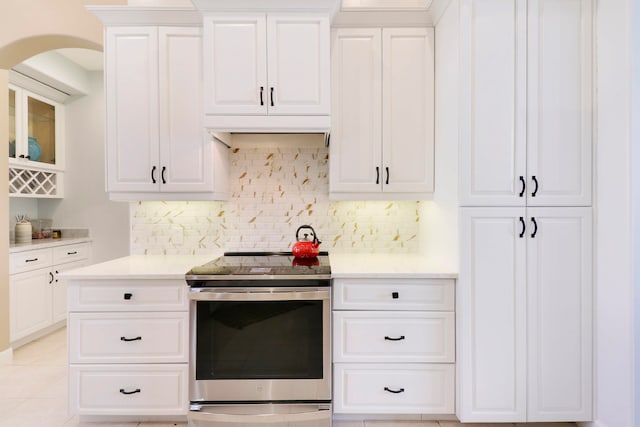 kitchen with white cabinets, light tile patterned flooring, backsplash, and electric stove