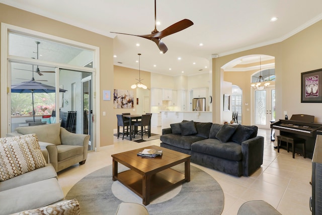 living room with ornamental molding, light tile patterned flooring, and ceiling fan with notable chandelier