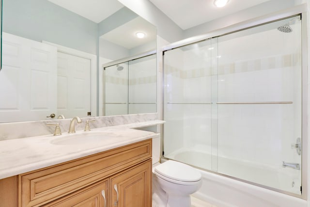 full bathroom featuring vanity, toilet, and shower / bath combination with glass door