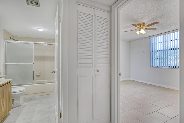 full bathroom with combined bath / shower with glass door, a textured ceiling, ceiling fan, tile patterned flooring, and toilet