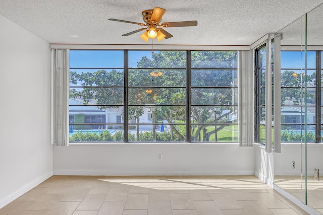 empty room with light tile patterned floors, a textured ceiling, and ceiling fan