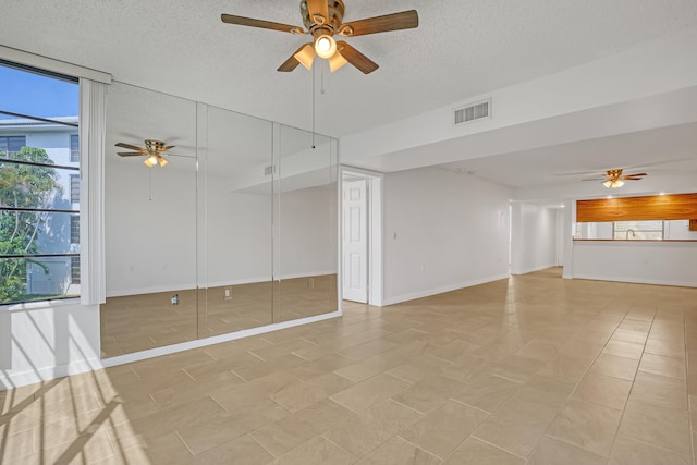 unfurnished living room with ceiling fan, light tile patterned floors, and a textured ceiling