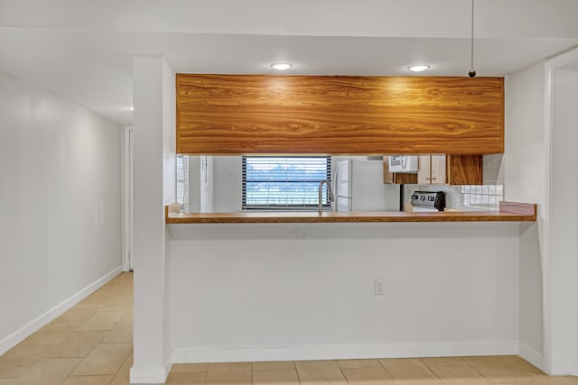 kitchen with kitchen peninsula, light tile patterned floors, and white appliances