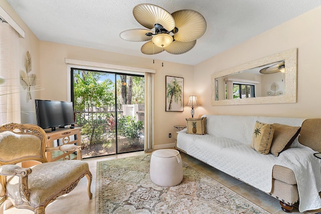 living room featuring a textured ceiling, dark tile patterned floors, and ceiling fan