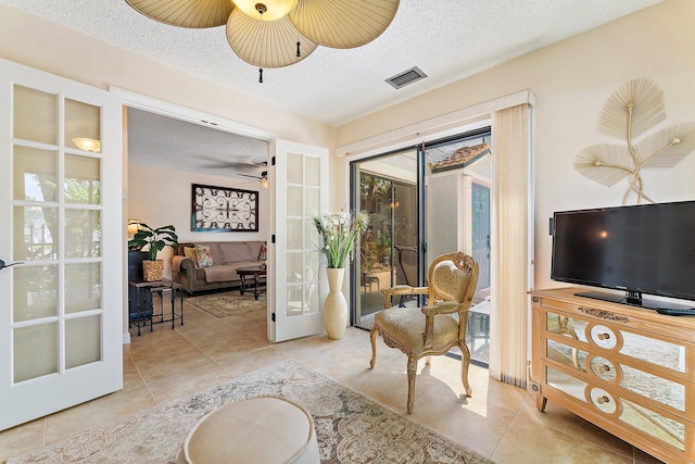 sitting room with french doors, light tile patterned flooring, and a textured ceiling