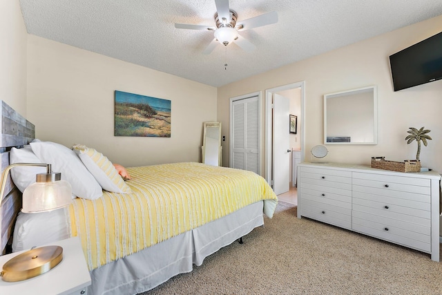 bedroom featuring ceiling fan, a textured ceiling, a closet, ensuite bath, and light colored carpet